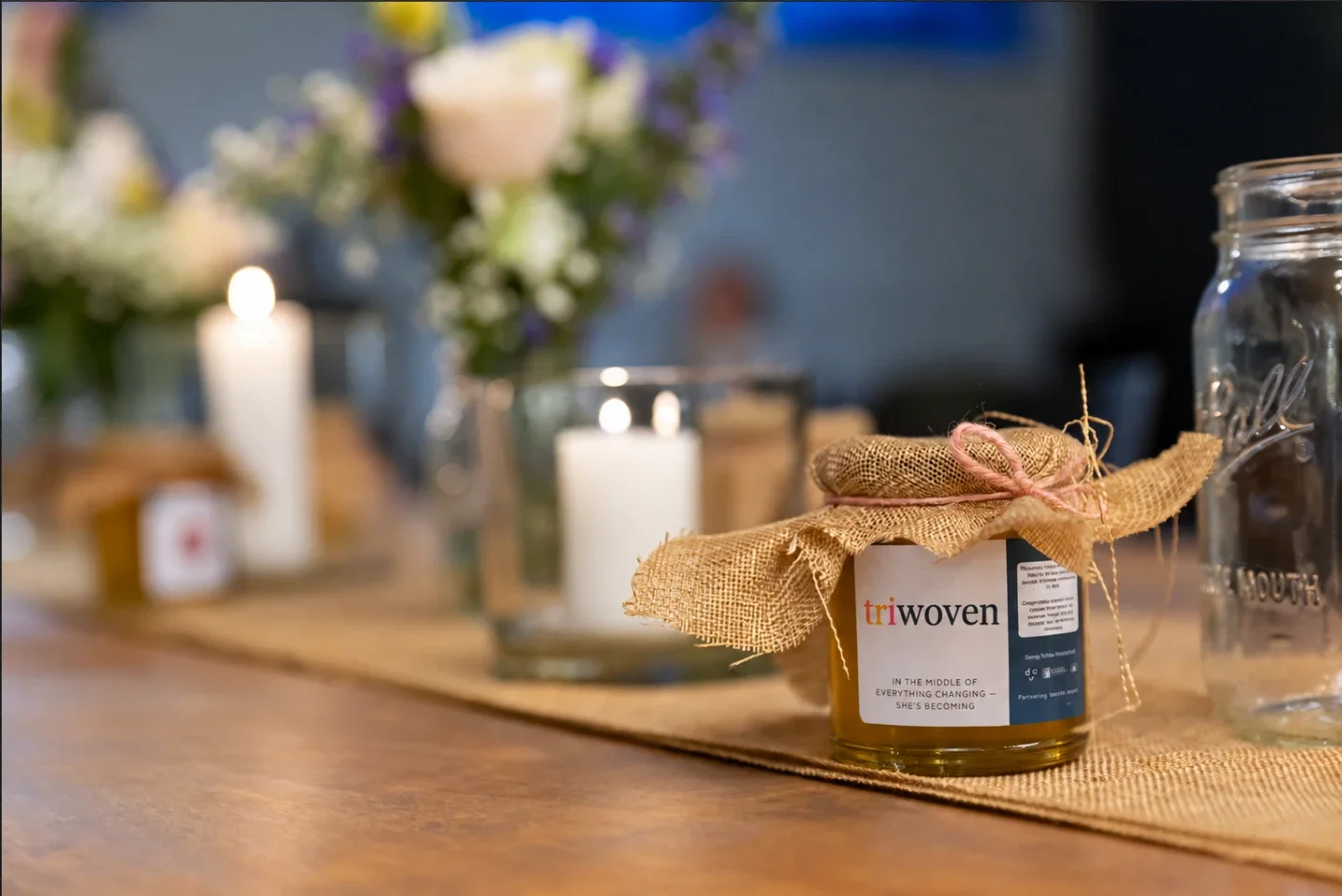 A triwoven honey jar on a candlelit table at a triwoven gathering